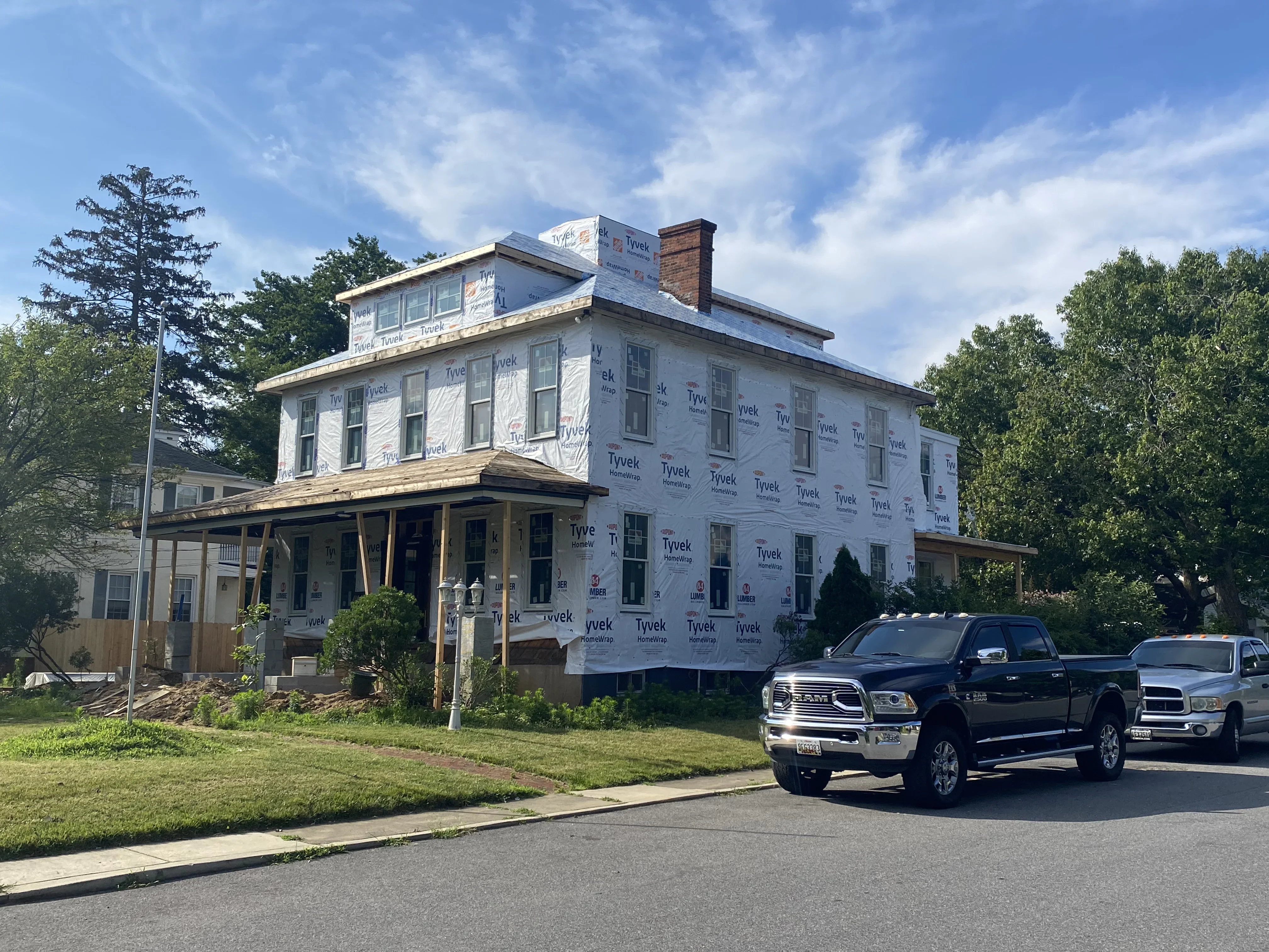 Two-story colonial home with new roof and Tyvek house wrap during renovation