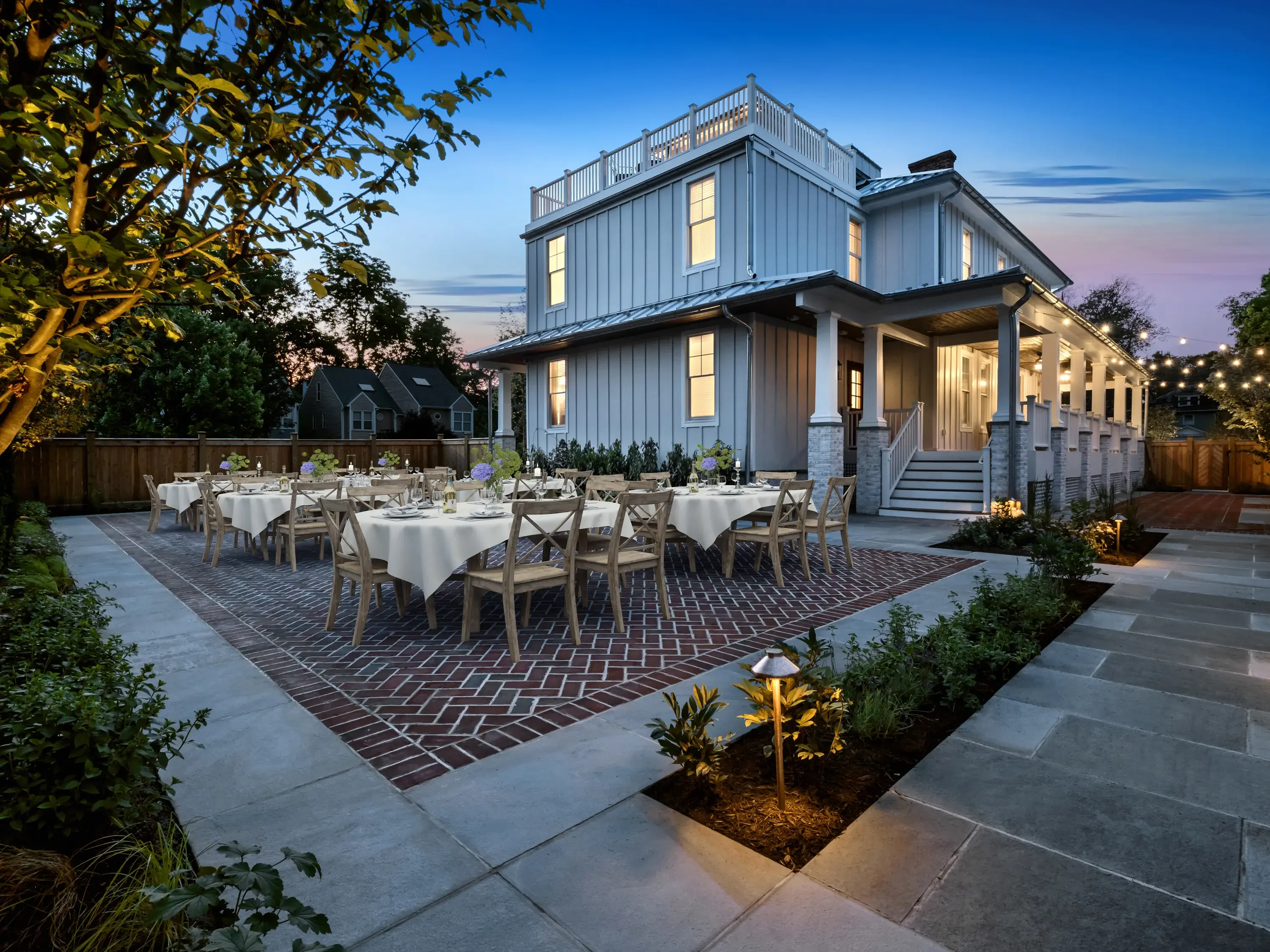Standing seam metal roof on modern farmhouse with vertical siding and stone base