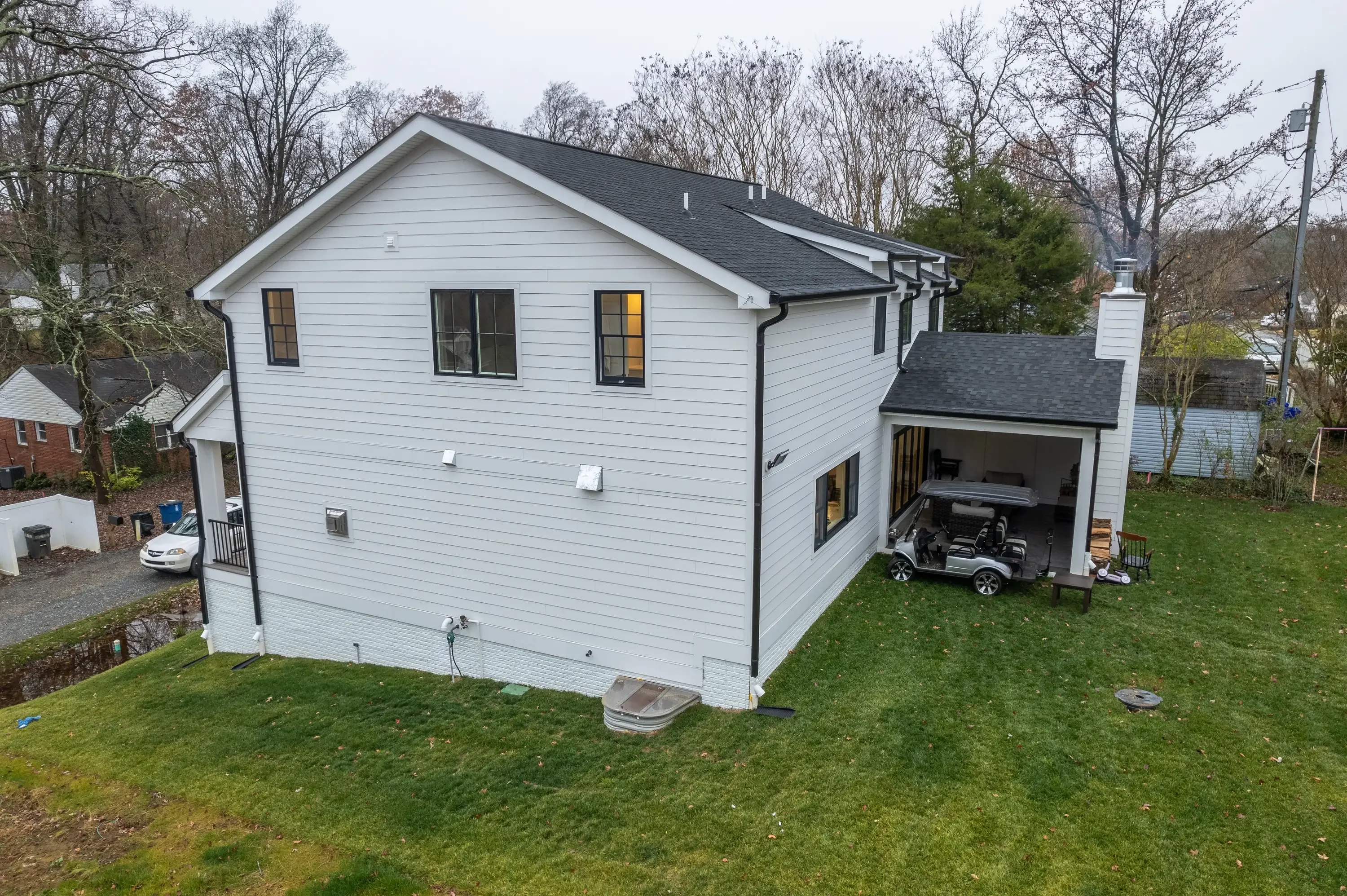 White sided home with dark gray asphalt shingle roof, black trim, and covered carport